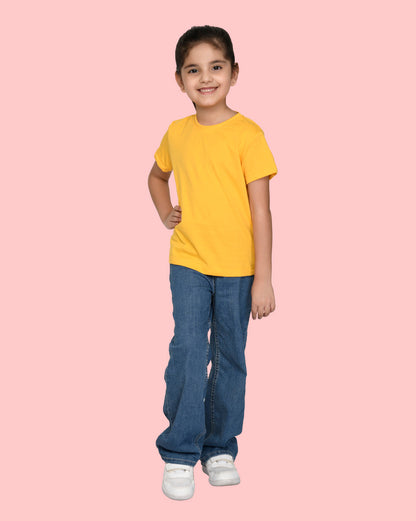 a little girl wearing a nusyl yellow short sleeve t shirt in standing position with blue jeans