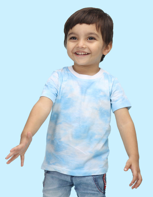a little boy standing up wearing blue color tie & dye t-shirt with his hands out.